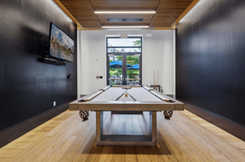 A room with a pool table and a television mounted on the wall.